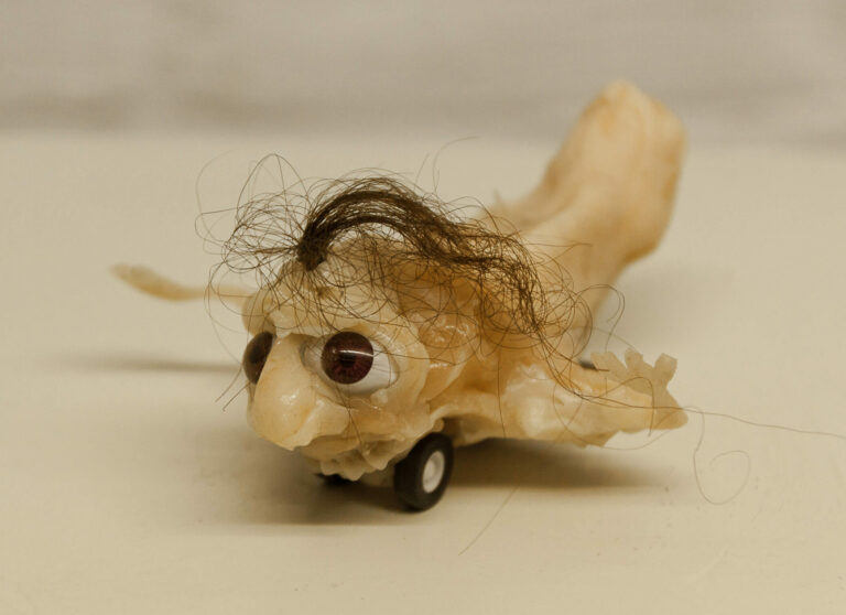 Skinny, creepy and somehow scary sculpture with teeth, eyes and hair. Handmade from silicone. Winds up like a toy car.